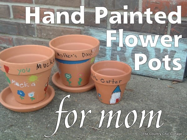 Picture of three terra cotta pots painted with different designs celebrating Mother's Day. 