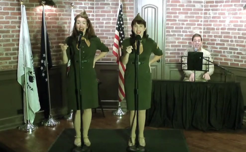 Two females dressed in military uniforms from WWII singing