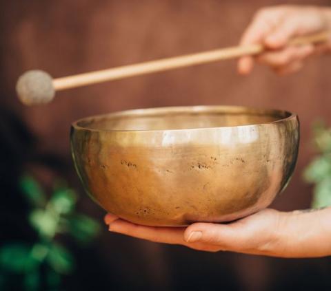 gold bowl with hand holding wooden stick that has a ball on it