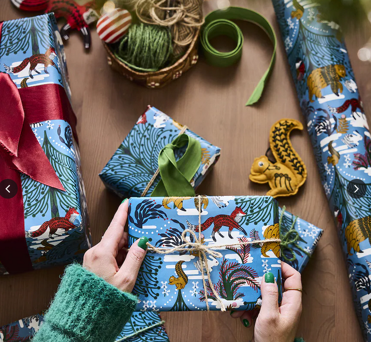 person wrapping holiday gifts with blue paper and bows